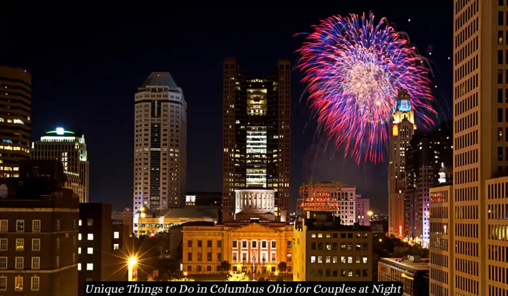 A vibrant fireworks display illuminates the night sky over downtown Columbus, Ohio, showcasing the city's skyline with prominent buildings. The bright colors of the fireworks contrast with the dark night, creating a festive atmosphere. Text: "Unique Things to Do in Columbus Ohio for Couples at Night.
