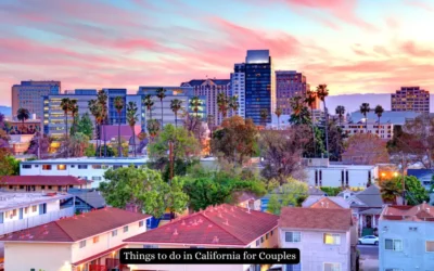 A vibrant cityscape of California at sunset, featuring tall buildings and palm trees with a foreground of residential houses. The sky is painted in hues of pink and orange. A banner reads, Things to do in California for Couples.