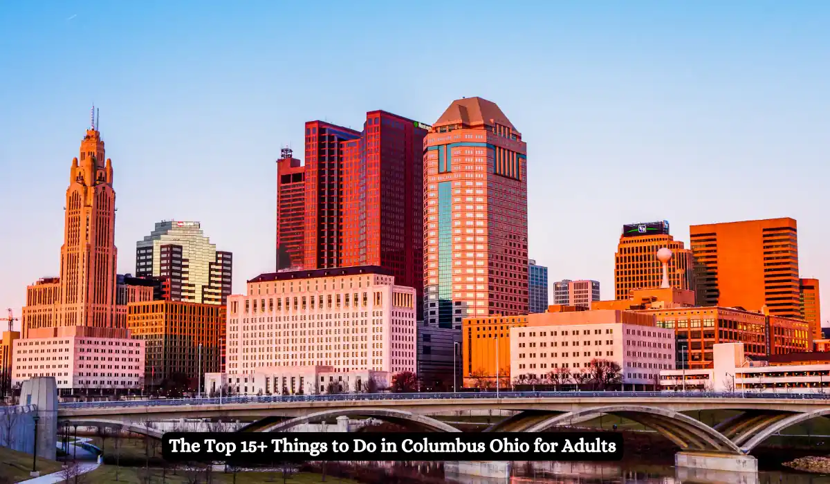 Skyline of Columbus, Ohio, featuring several modern high-rise buildings against a clear blue sky. A bridge spans across the foreground. Text at the bottom reads, The Top 15+ Things to Do in Columbus Ohio for Adults.