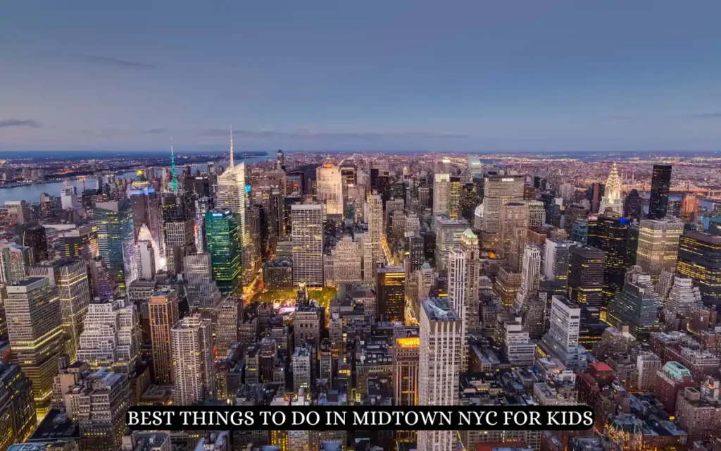 Aerial view of Midtown New York City at dusk, showcasing a dense skyline filled with illuminated skyscrapers against a fading blue sky. Text overlay at the bottom reads, BEST THINGS TO DO IN MIDTOWN NYC FOR KIDS.